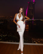 Woman in a white outfit posing on a rooftop with a cityscape and illuminated building in the background.