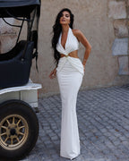 Woman in a white dress standing next to a vintage cart on a stone pavement.